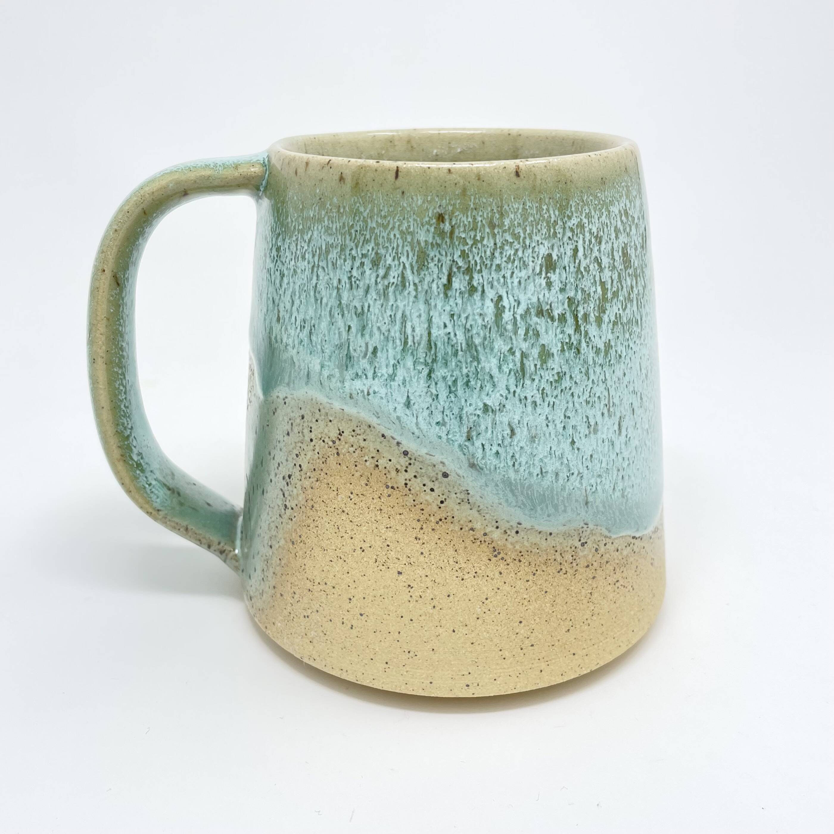 Handmade mug with a seafoam-green glaze over a sandy cream base