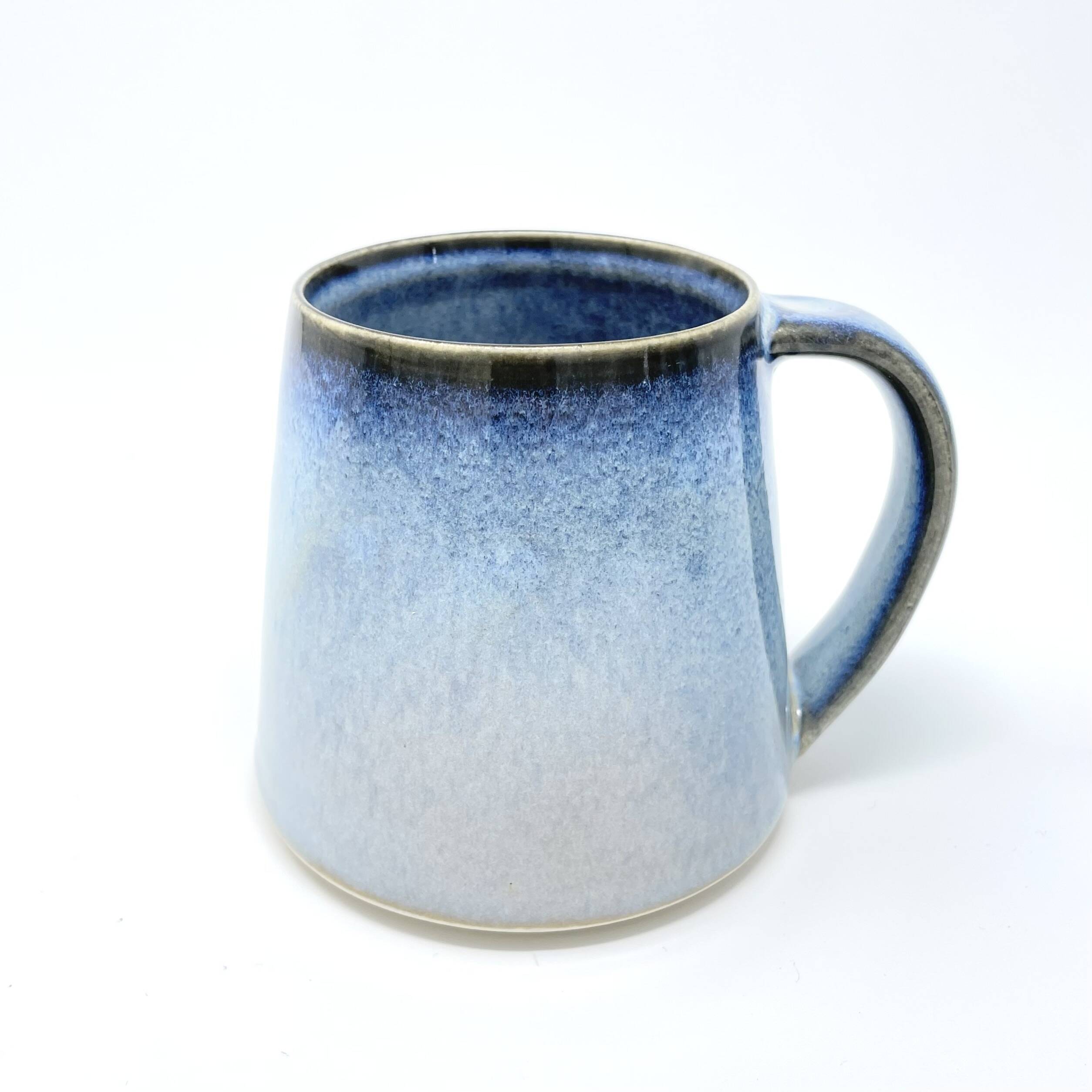 Handmade mug with a blue glaze fading to white and a dark rim