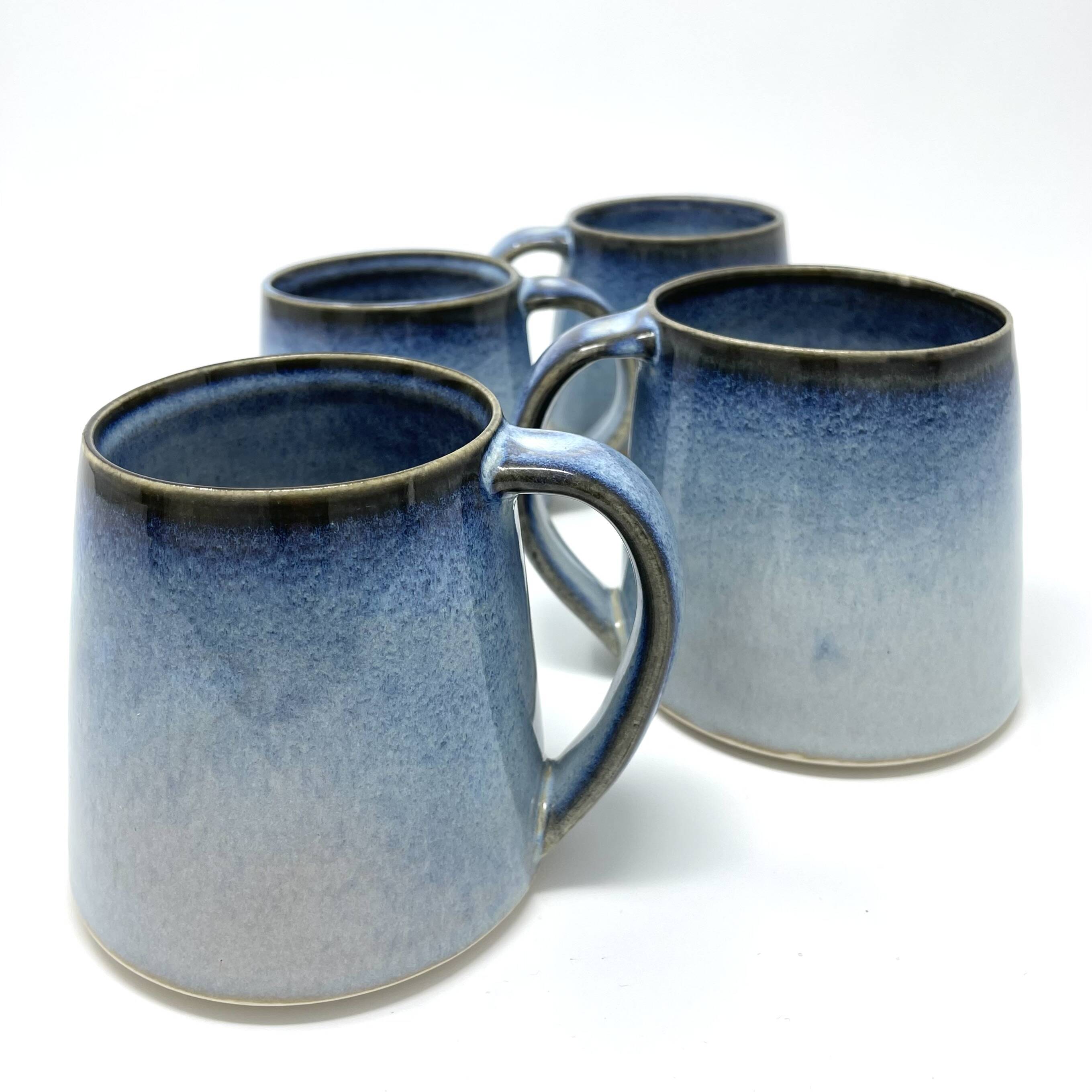 Four mugs with a blue ombre glaze fading to white