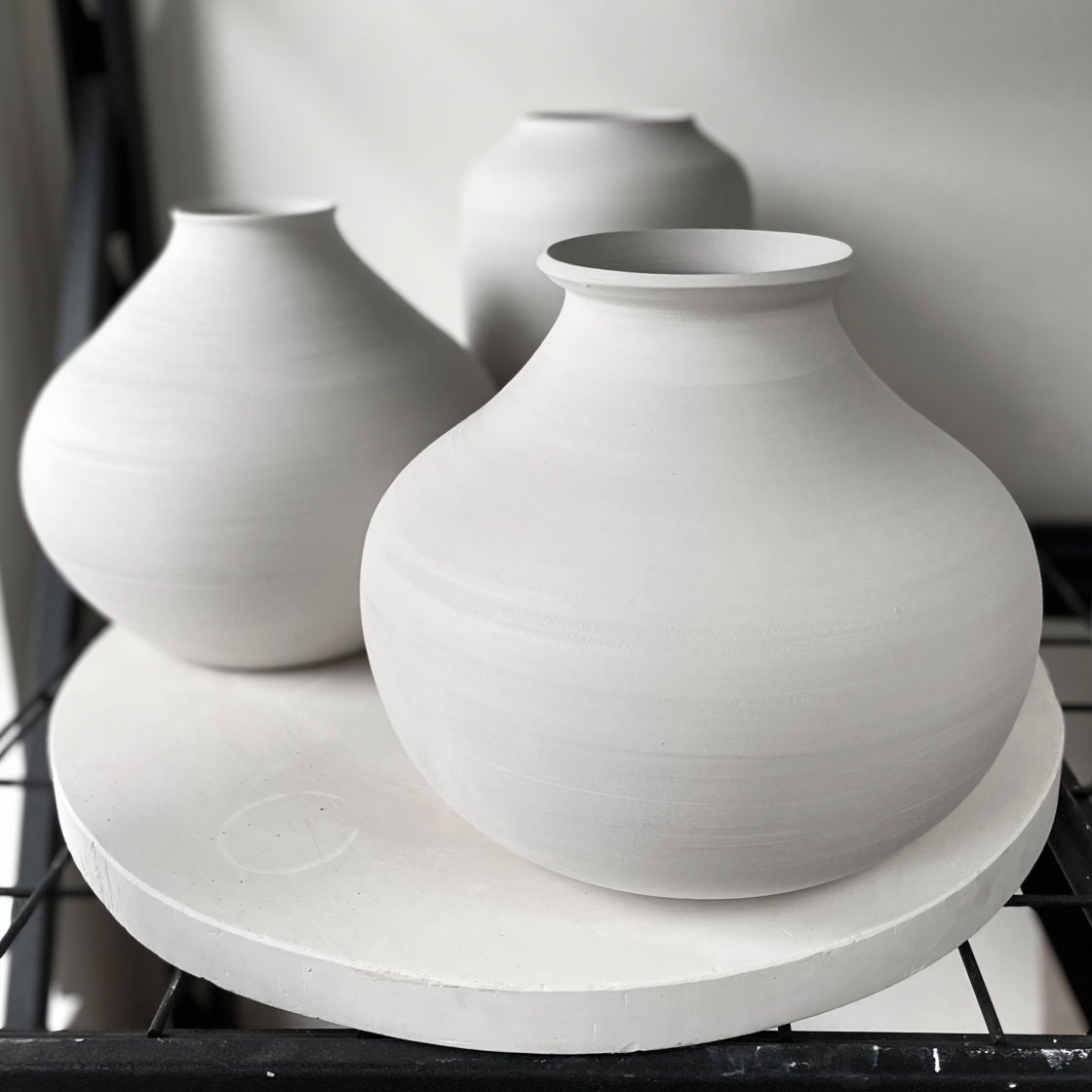 Two rounded matte-white vases on a white platter