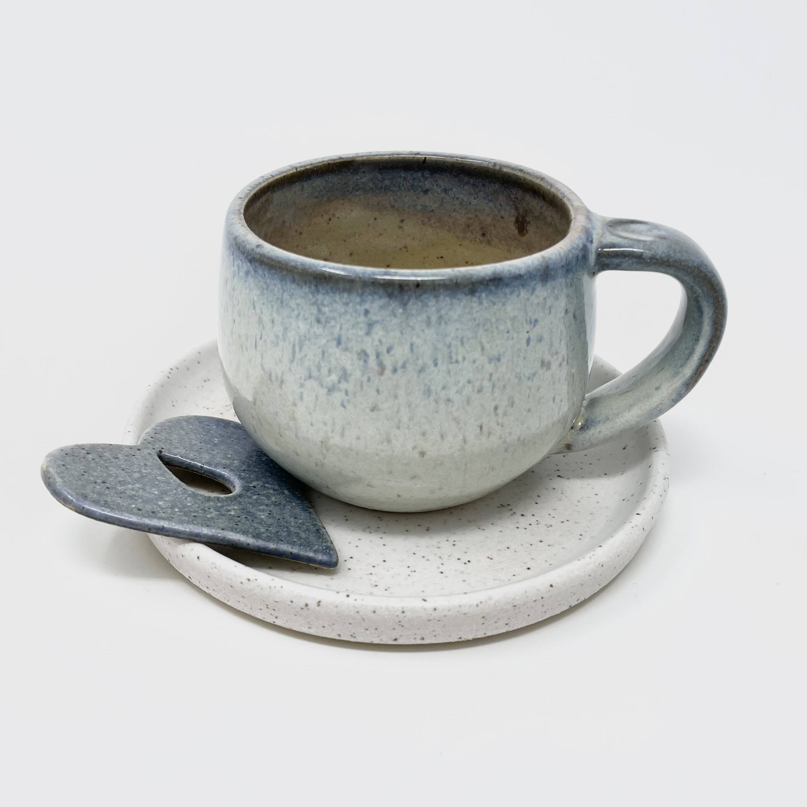 Blue-grey speckled cup and saucer with a matching spoon