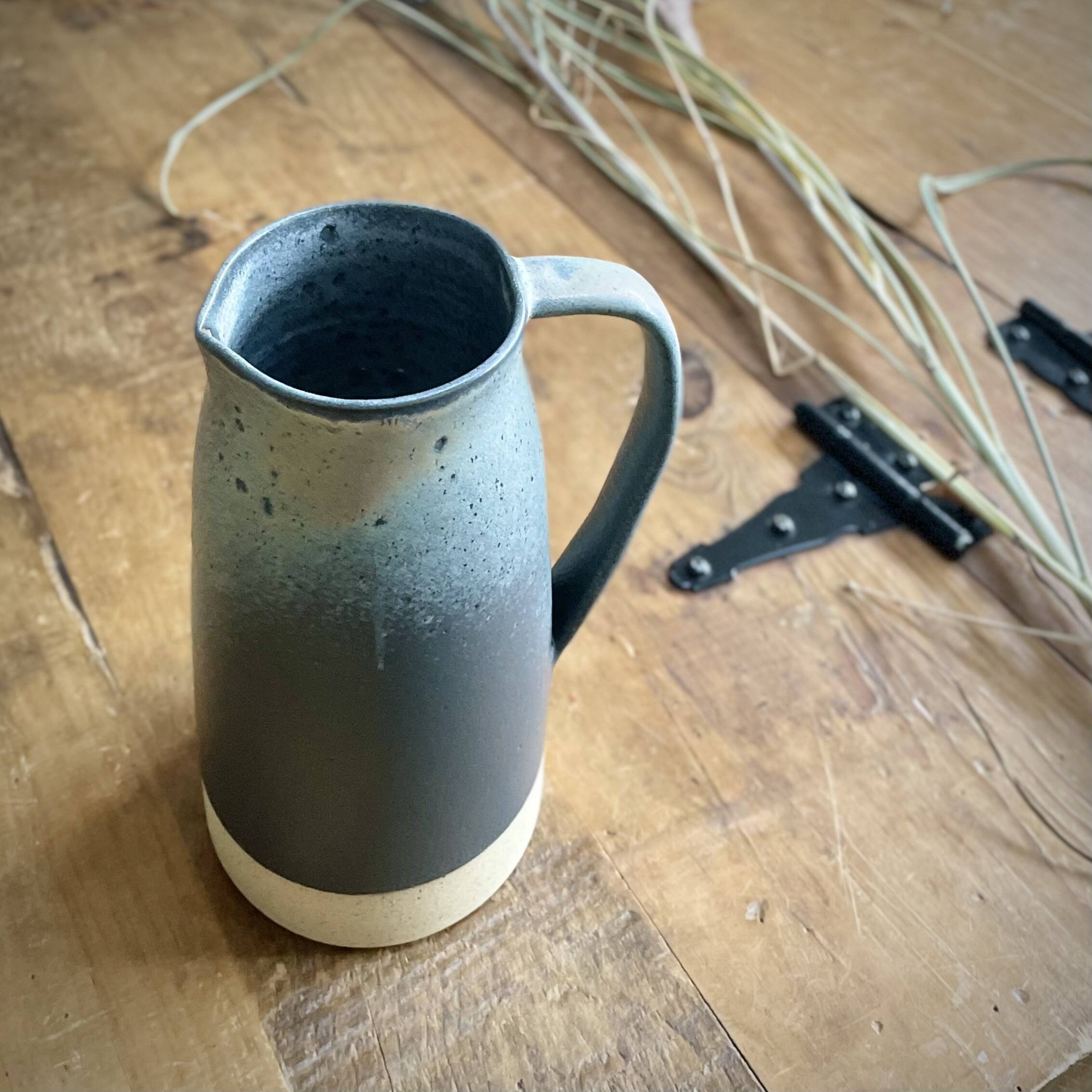 Tall handmade pitcher with a blue speckled glaze and white base