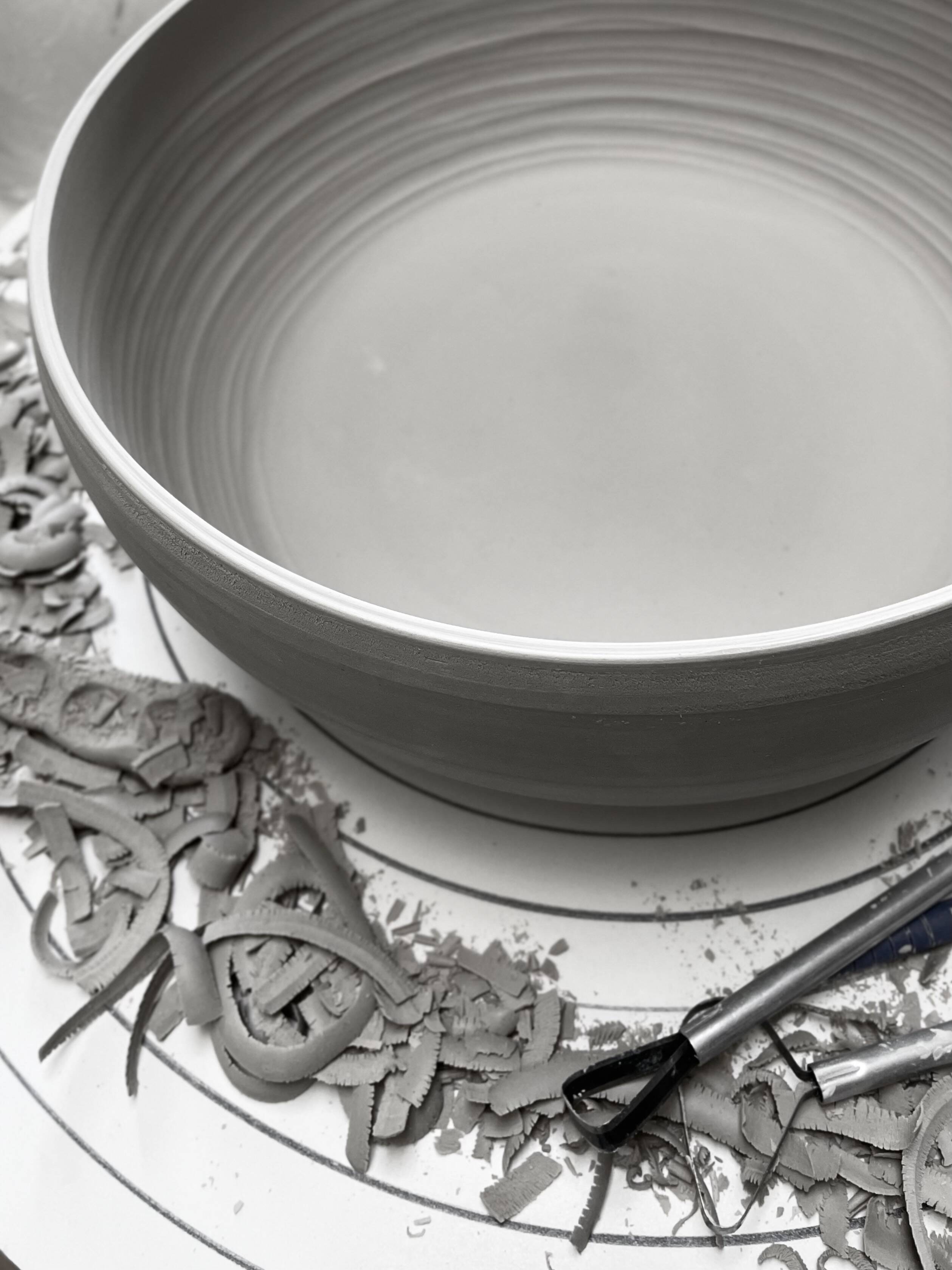 Grey bowl surrounded by clay trimmings in the studio