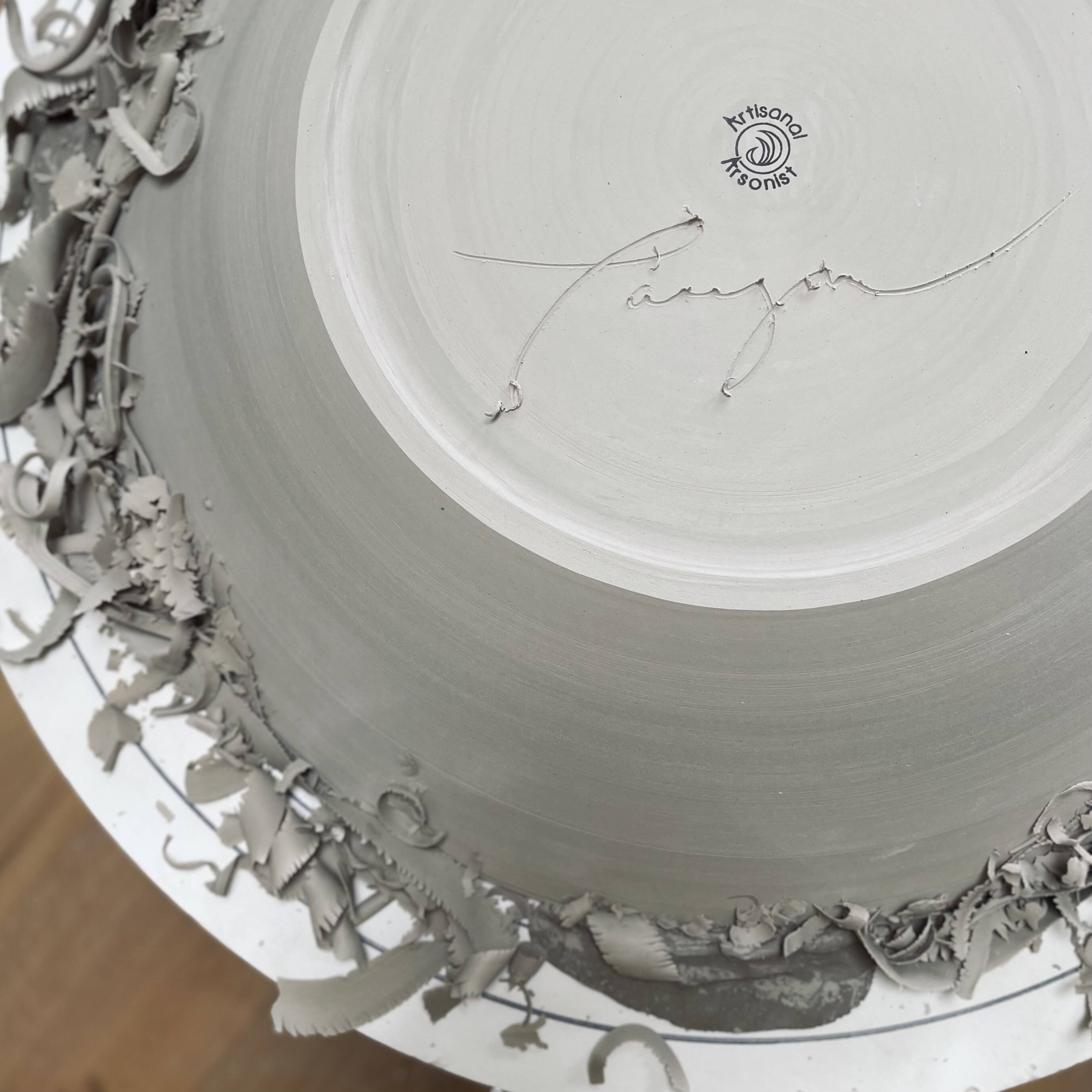 Close-up of a large bowl on the pottery wheel, signed by the artist