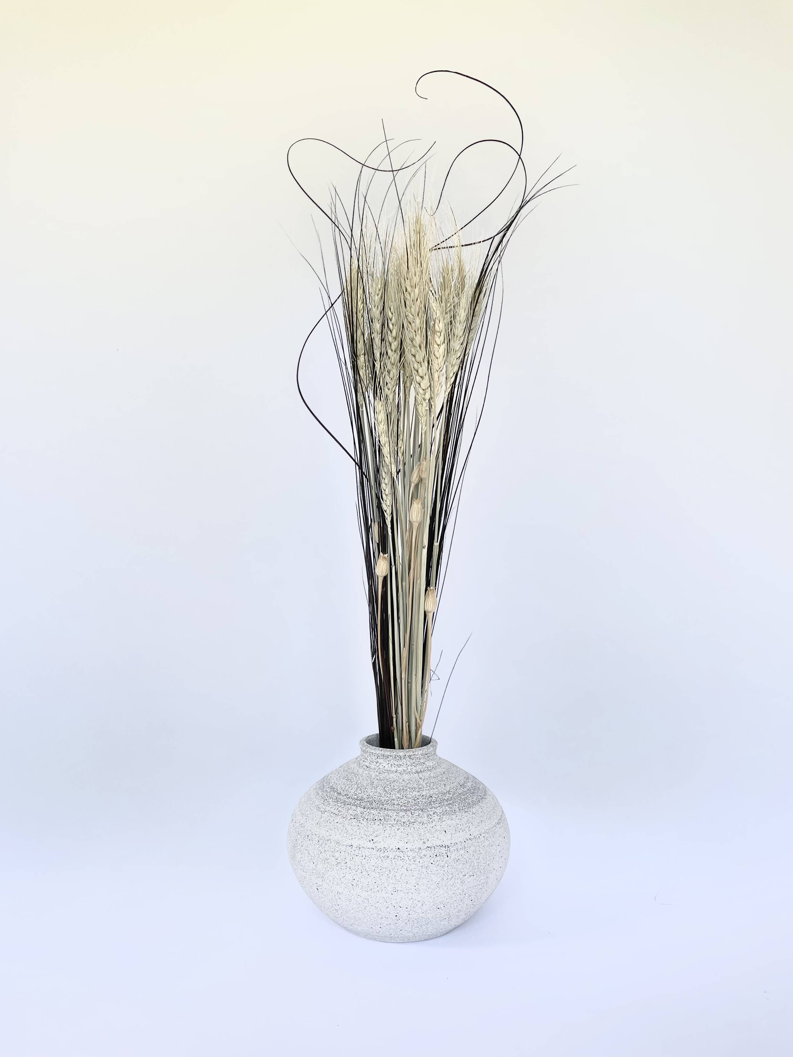 Small white vase holding a tall spray of dried grass