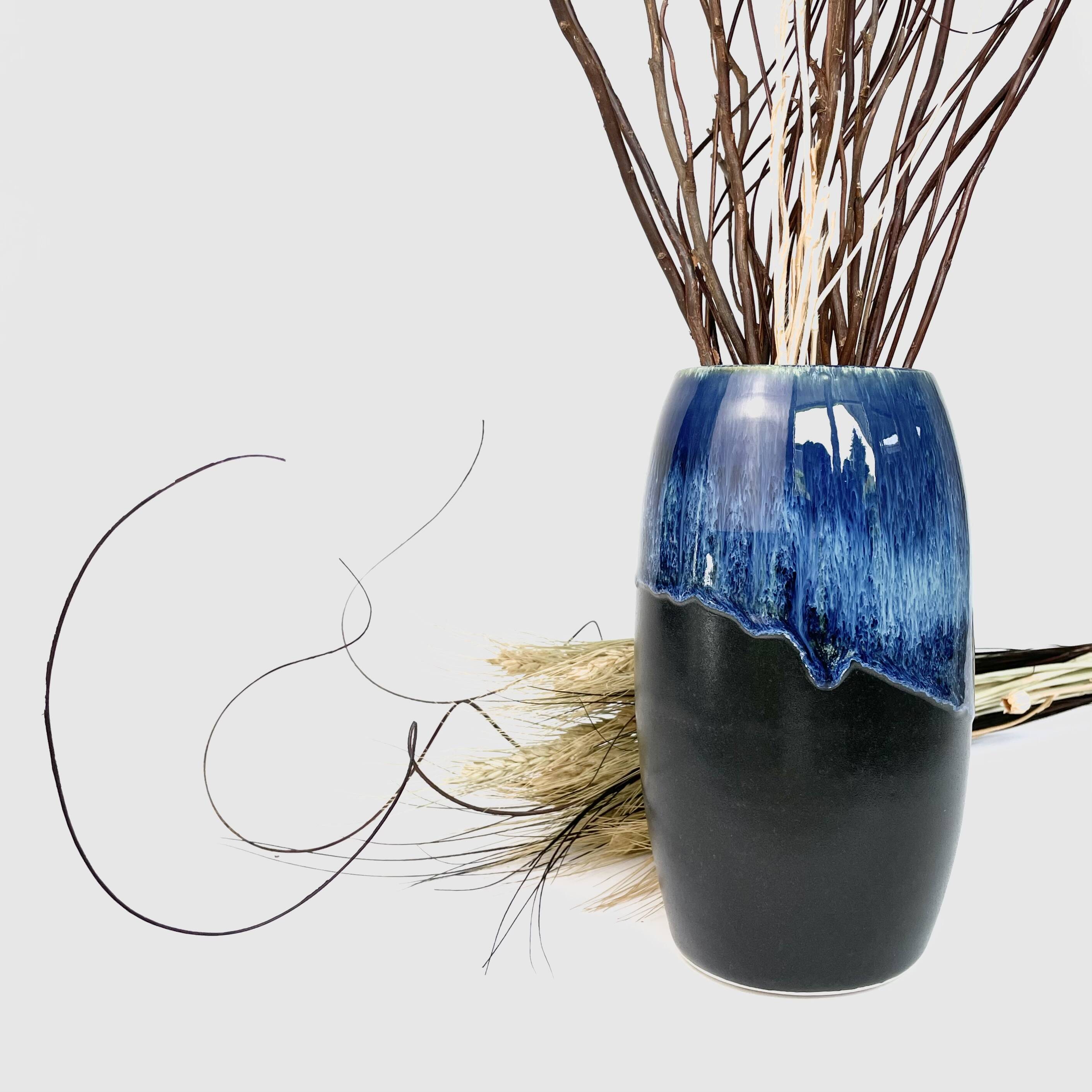 Dark blue drip-glazed vase holding dried branches and wheat