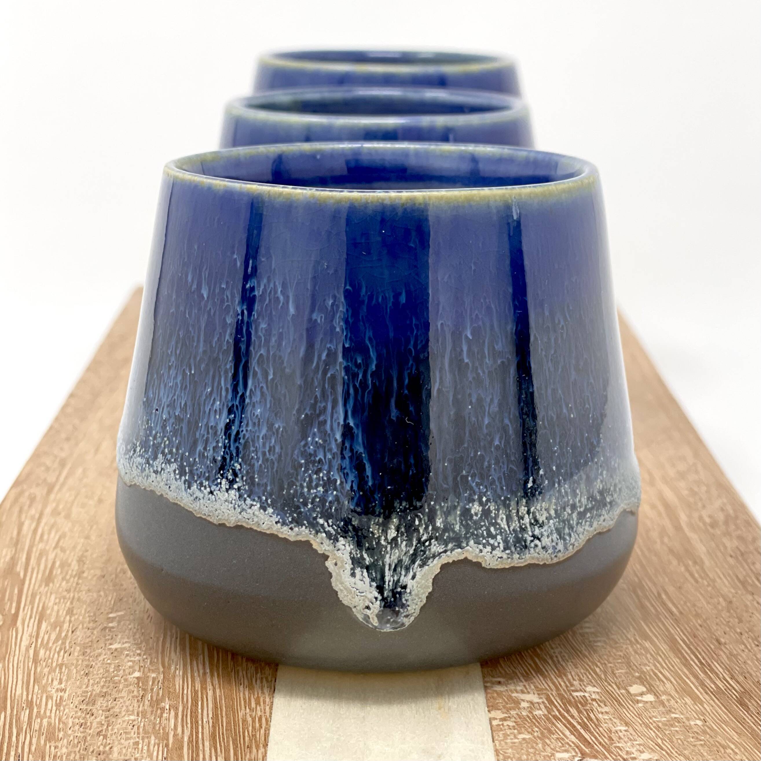 Nested cups with a cobalt-blue drip glaze over grey on a wooden board