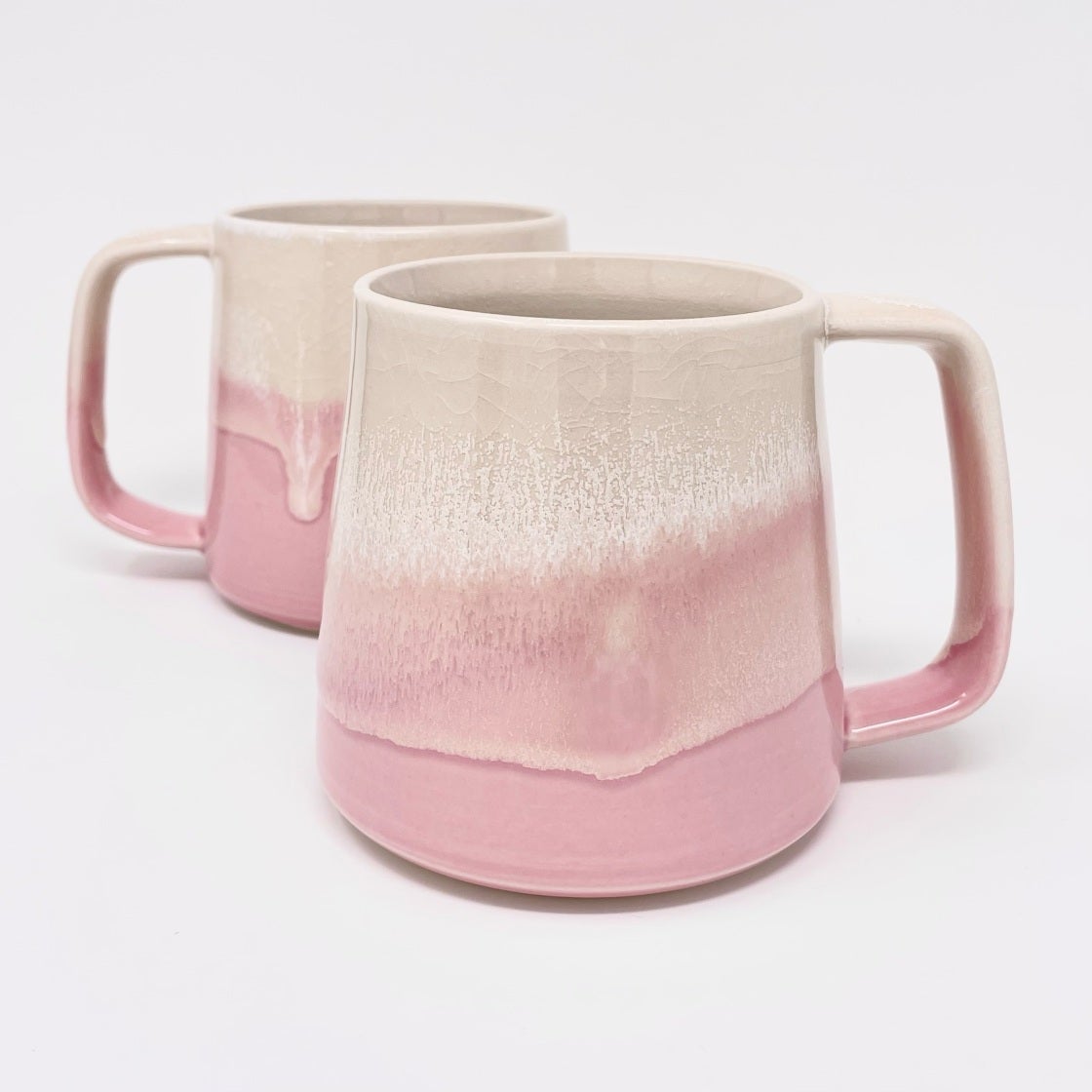Two mugs with a glaze fading from cream to soft pink