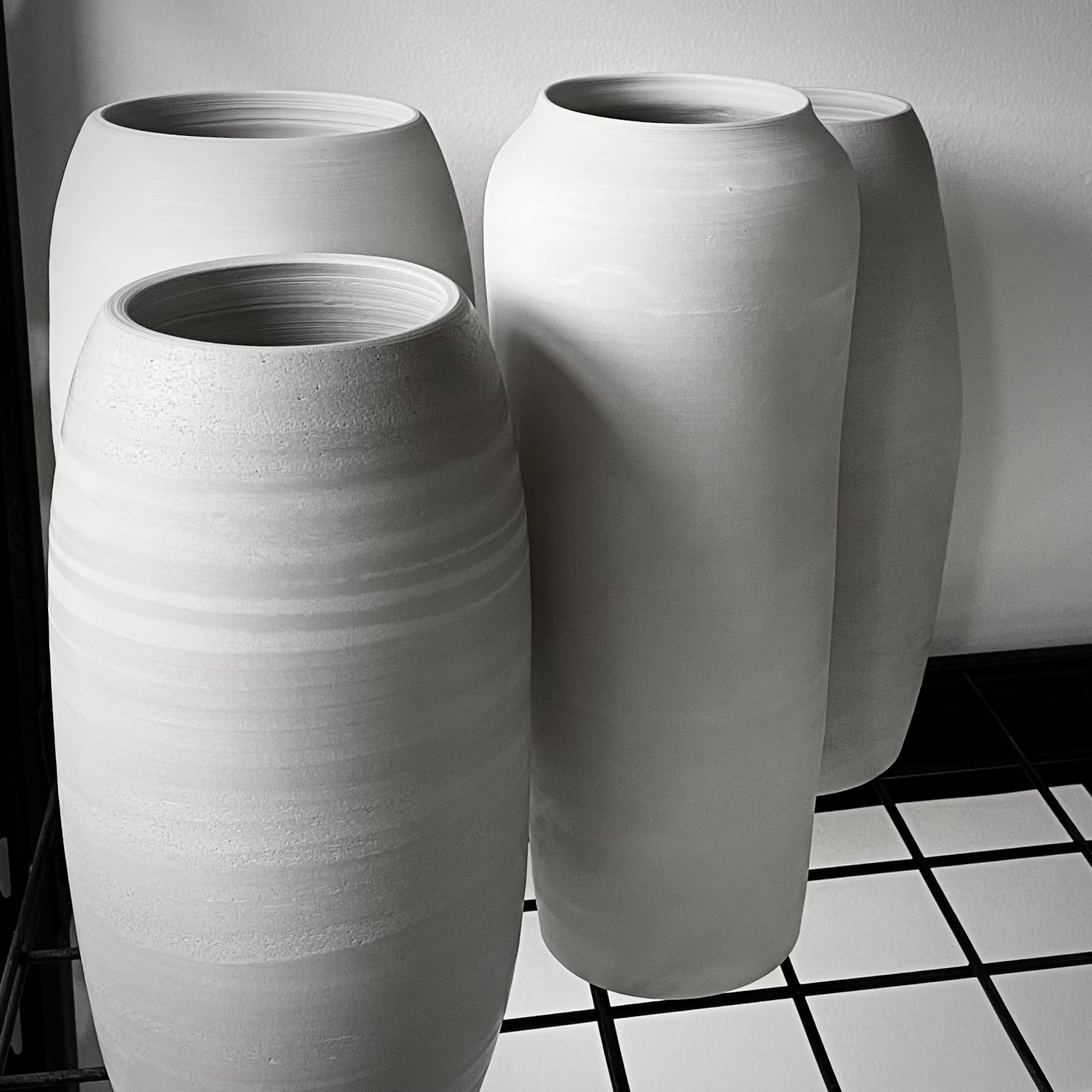 Three tall cylindrical vases with a grey matte finish