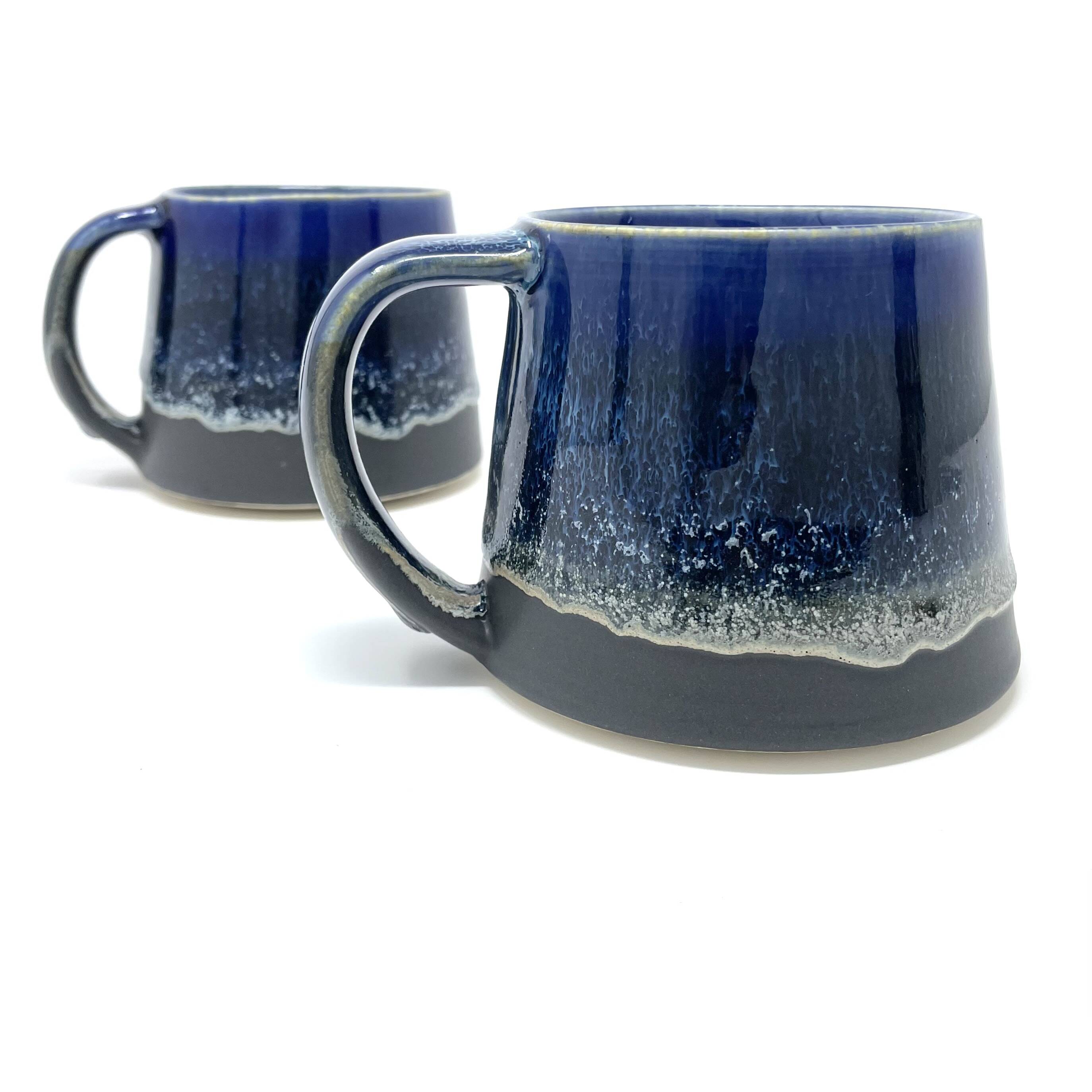 Two mugs with a dark cobalt-blue glaze over a dark base