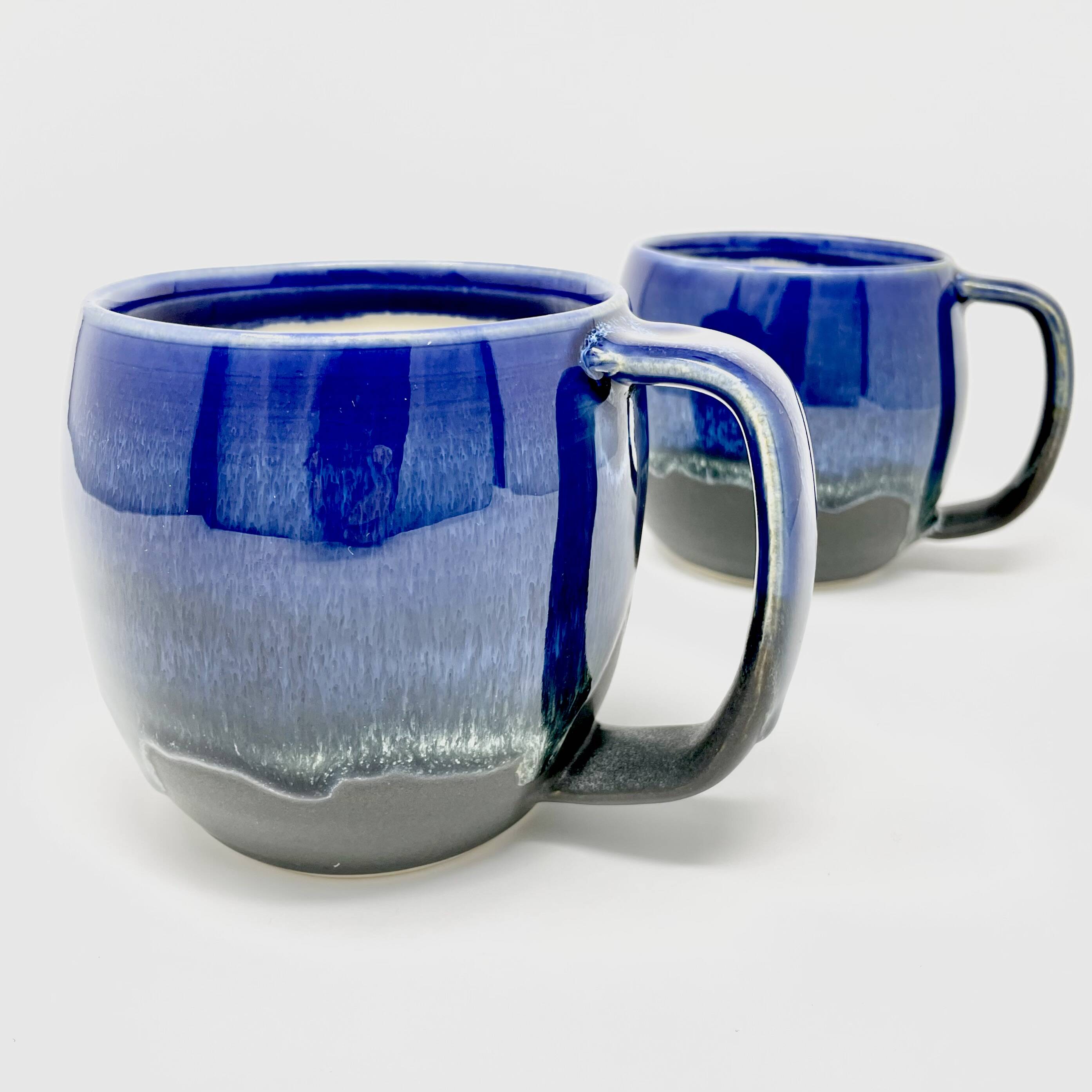 Two mugs with a cobalt-blue glaze and lighter drip over grey